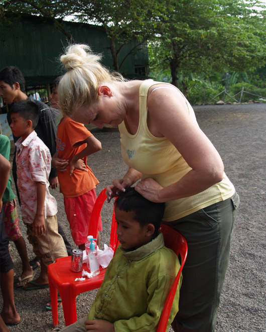 Katie checking for head  lice at Cambodia orphanage
